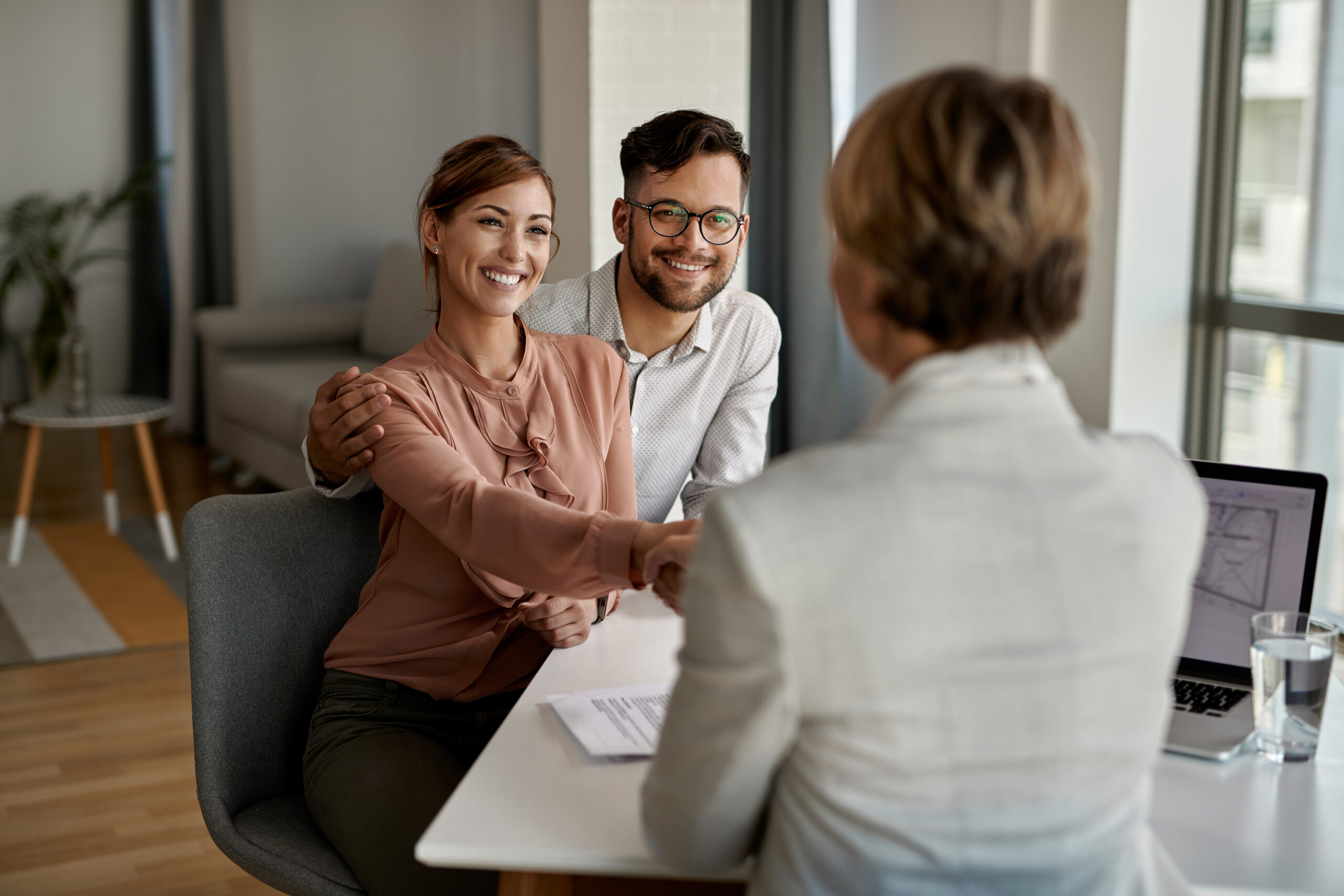 Young Happy Couple Shaking Hands With Insurance Agent Meeting Office Scaled